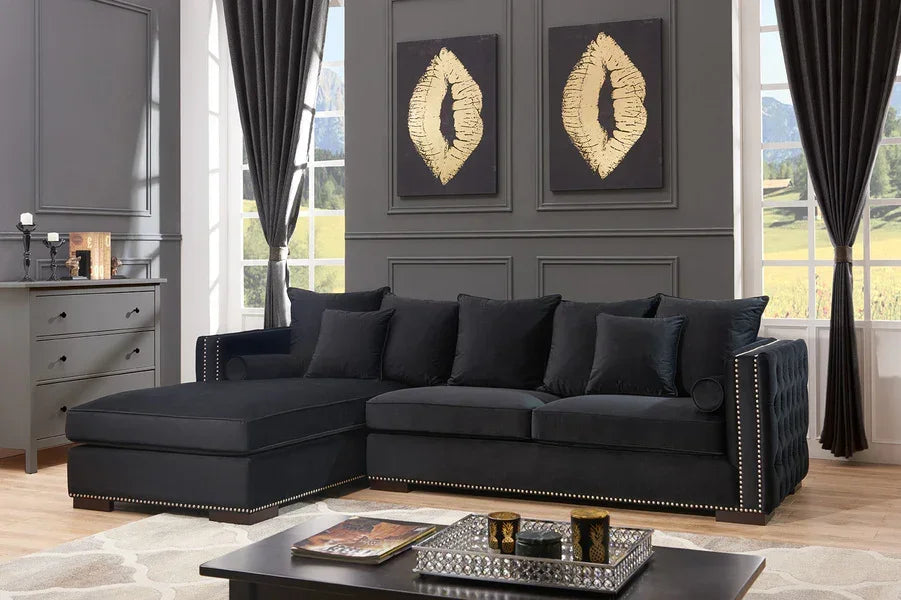 Black velvet corner sofa with studded trim in modern living room with grey panel walls