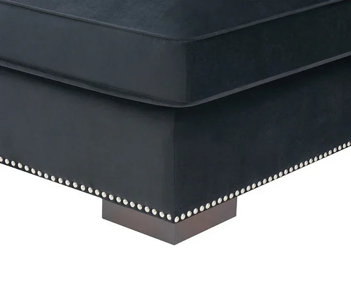 Black velvet sofa corner with silver stud detailing and dark wooden base