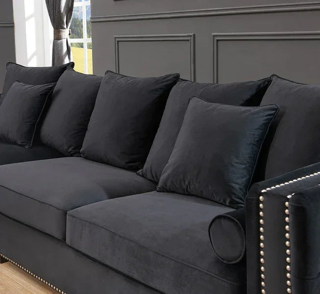 Black velvet sofa with studded arms and matching scatter cushions in a modern living room