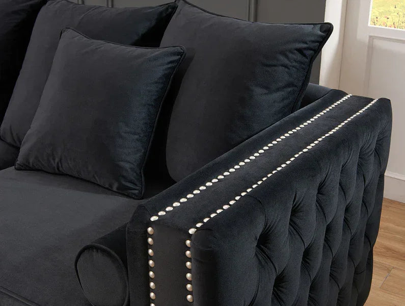 Black velvet sofa with buttoned armrest and silver stud detailing in living room setting