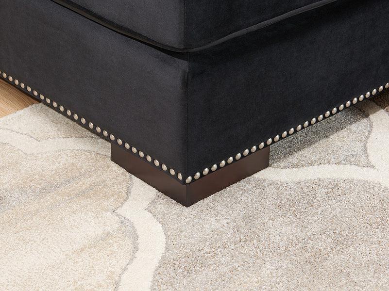 Black fabric sofa corner with studded trim on a beige patterned rug