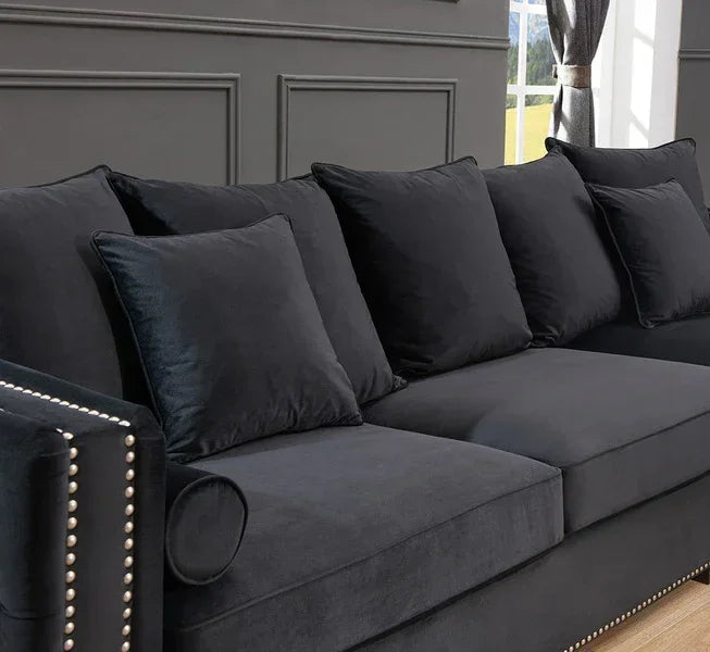 Black velvet sofa with cushions and studded armrest in modern living room