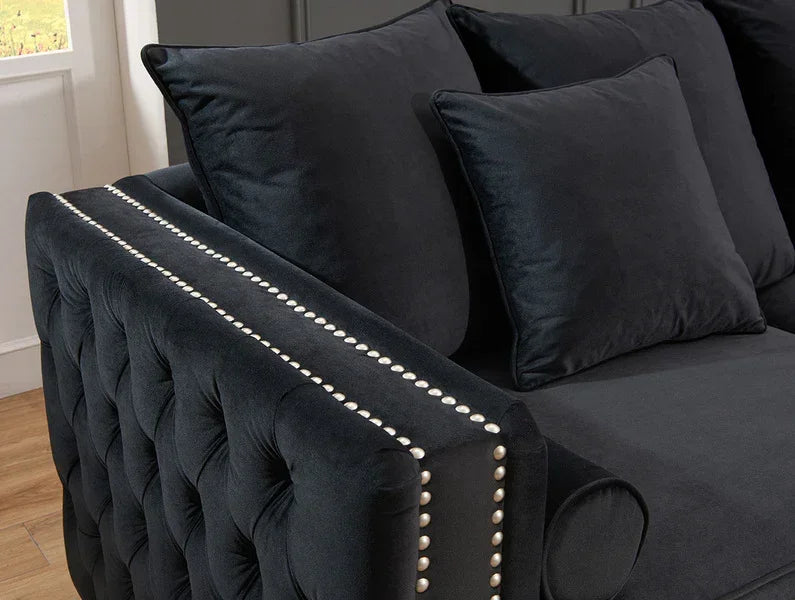 Black velvet sofa with silver stud detail and tufted armrest, shown in lounge setting
