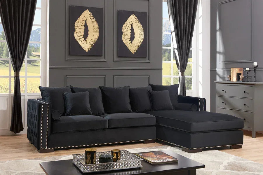 Black velvet corner sofa with studded trim in modern living room with grey walls and decor