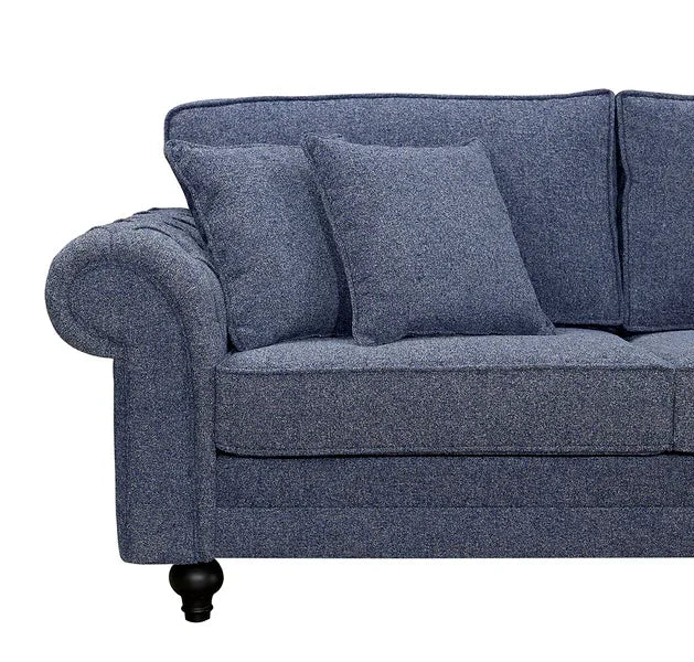 Blue fabric sofa with rolled armrest and matching scatter cushions, partial front view