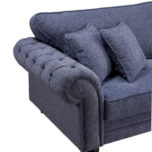 Blue fabric sofa with tufted armrest and matching scatter cushions, close-up angle