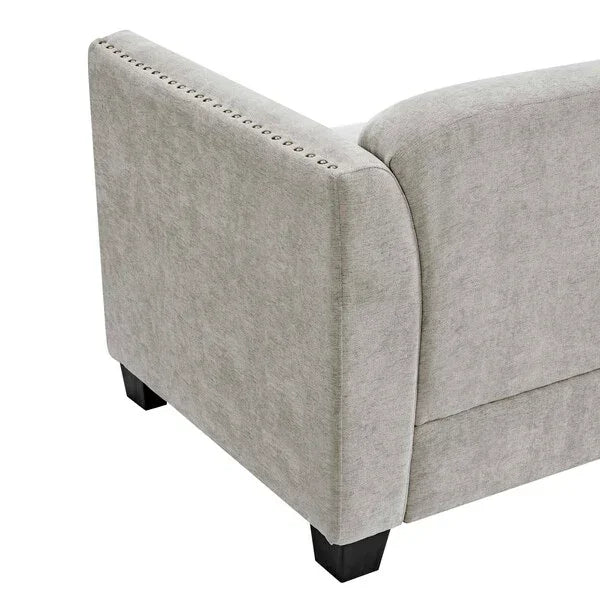 Light grey fabric sofa arm with nailhead trim and black wooden leg closeup