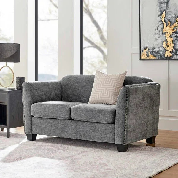 Grey fabric sofa with nailhead trim and accent cushion in modern living room setting