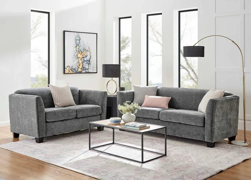 Grey fabric sofa set with cushions in modern living room, glass coffee table in center