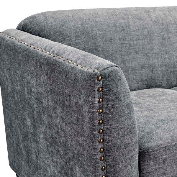 Grey fabric sofa arm with brass stud detailing and soft upholstery