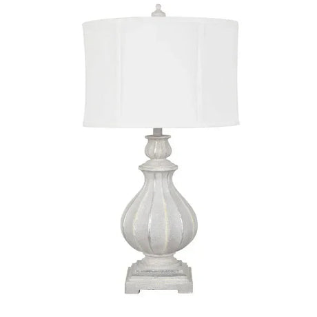 Distressed white table lamp with fluted urn-shaped base and white drum shade, front view