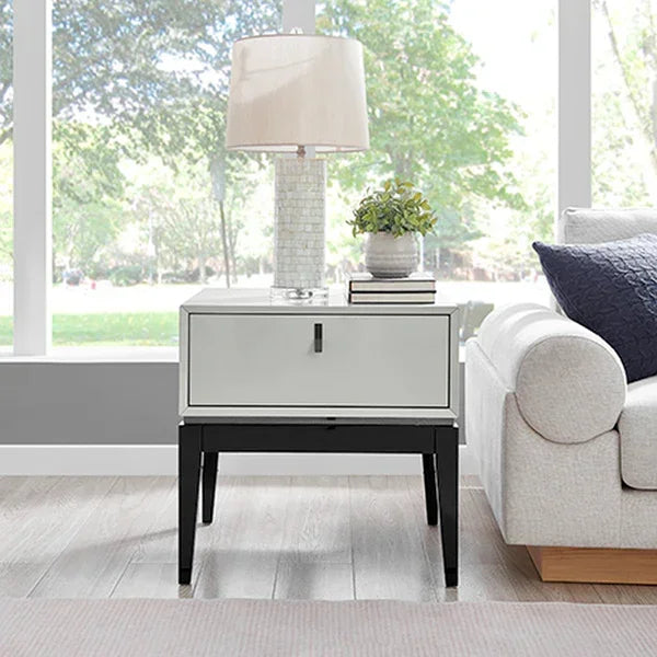 Mirrored bedside table with black legs beside sofa, decorative lamp and plant on top