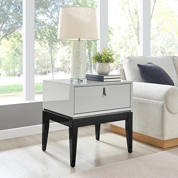 Gloss white bedside table with black legs, lamp and decor in modern living room