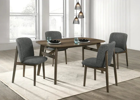 Modern dining table with four gray upholstered chairs on beige rug in bright dining room