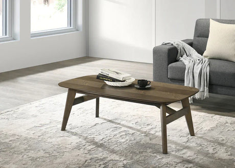 Modern wooden coffee table with books and cup beside grey sofa in living room