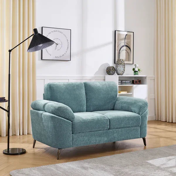 Teal fabric sofa with cushioned arms and metal legs in bright living room with floor lamp