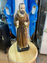 Brown robed saint figurine holding rosary, displayed on wooden stand in retail store