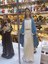 Resin figurine of woman in white and blue robe displayed on shelf with measuring tape