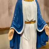 Religious figurine in white robe with blue cloak, gold belt, hands open on table