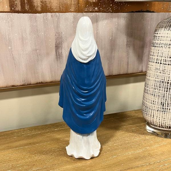 Ceramic statue draped in blue and white, displayed on wooden table against modern decor