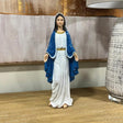 Religious statue with blue and white robe on wooden table beside patterned lamp