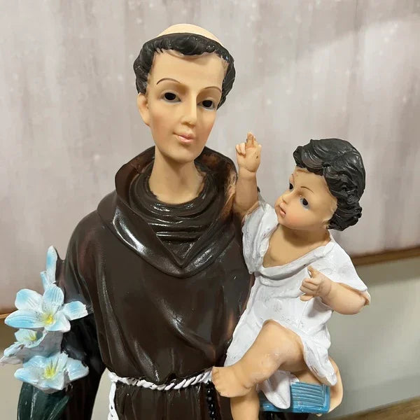Religious figurine of saint in brown robe holding child and blue lilies