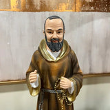 Bearded monk figurine in brown robe holding prayer beads, displayed against a neutral background