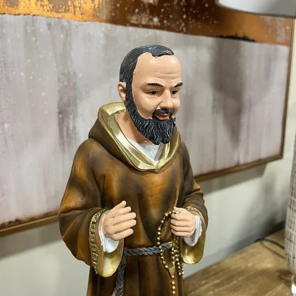 Brown monk figurine holding rosary beads on wooden table