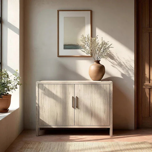 Light wood sideboard cabinet with double doors, vase on top, sunlit modern entryway