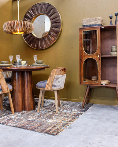 Wooden dining table and chairs with glass cabinet and round mirror in dining room