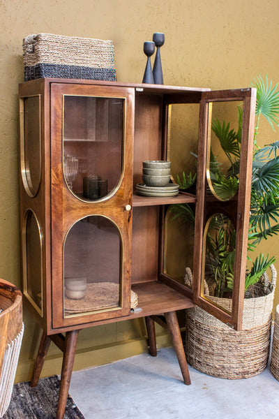 Brown wooden cabinet with glass doors, decorative bowls inside, basket on top
