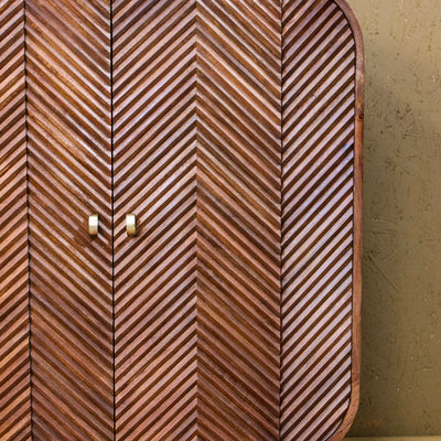 Wooden cabinet with chevron pattern and rounded edges on metal legs