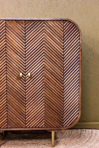 Wooden cabinet with chevron pattern and rounded edges on metal legs