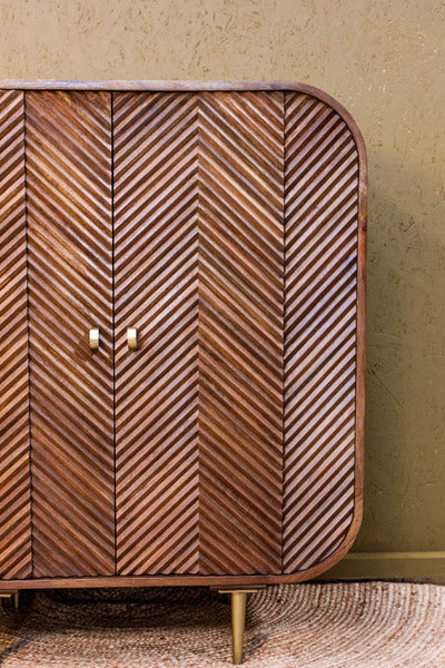 Wooden cabinet with chevron pattern and rounded edges on metal legs