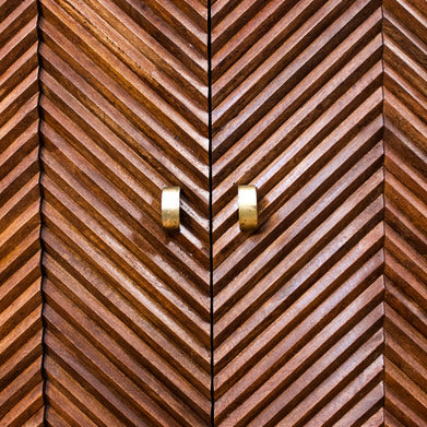 Close-up of wooden cabinet doors with layered chevron pattern and brass handles
