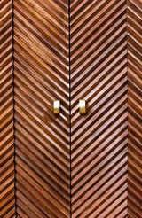 Close-up of wooden cabinet doors with layered chevron pattern and brass handles