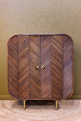 Wooden cabinet with layered chevron pattern doors and rounded edges on brass legs