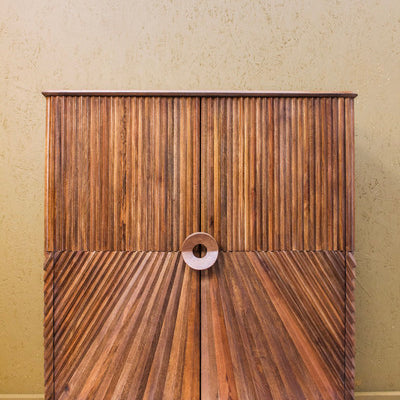 Wooden cabinet with diagonal and vertical carved patterns and round central handle