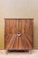 Wooden cabinet with diagonal and vertical carved patterns and round central handle