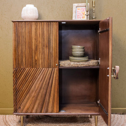 Wooden cabinet with two doors, one open showing two shelves with bowls and a basket