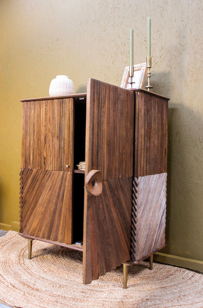 Wooden cabinet with diagonal chip design and brass legs on woven rug