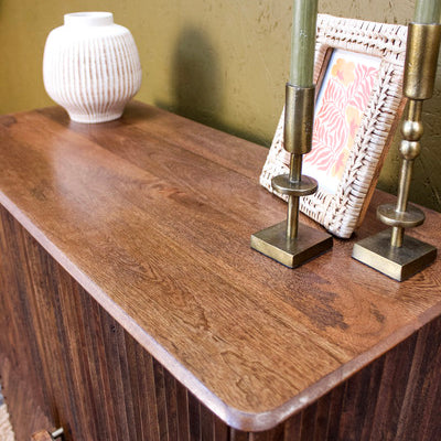Wooden cabinet top with decorative white vase, photo frame and brass candle holders