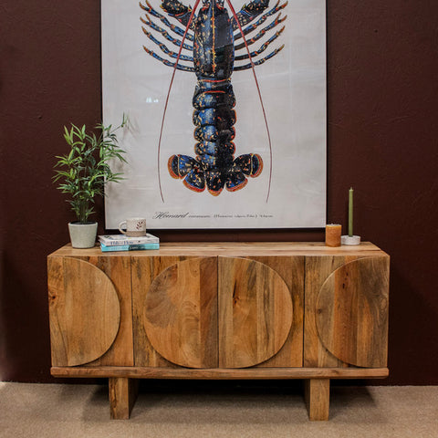 Wooden sideboard with oval door designs against dark wall with lobster artwork
