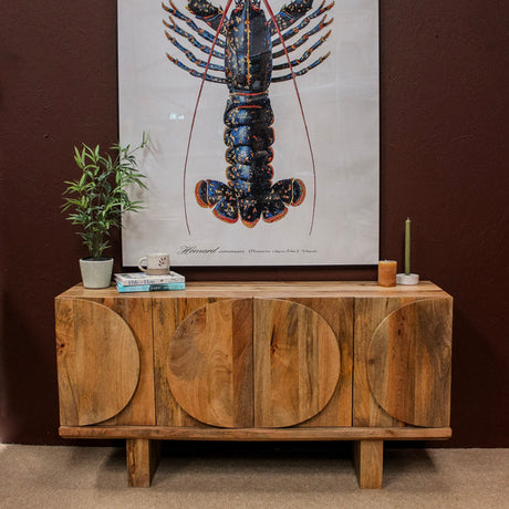 Wooden sideboard with oval door designs against dark wall with lobster artwork