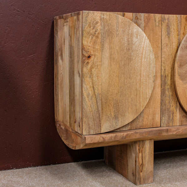 Close-up of wooden sideboard with oval design and thick legs against a textured wall
