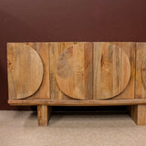 Wooden sideboard with circular carved doors on carpeted floor