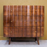 Wooden three drawer cabinet with curved fronts and small round knobs