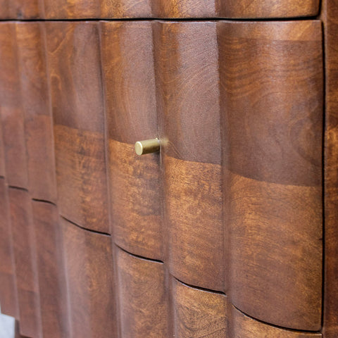 Close-up of curved wooden drawer front with round metal handle