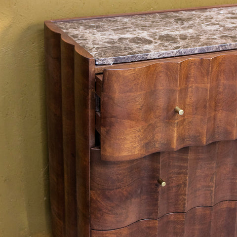 Close-up of wooden cabinet drawers with brass handles and marble top