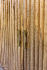 Wooden cabinet doors with vertical capsule-shaped grooves and brass handles
